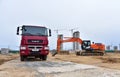 Red dump truck KAMAZ-65801-002-68ÃÂ¢5 8Ãâ¦4 and excavator HITACHI on construction site